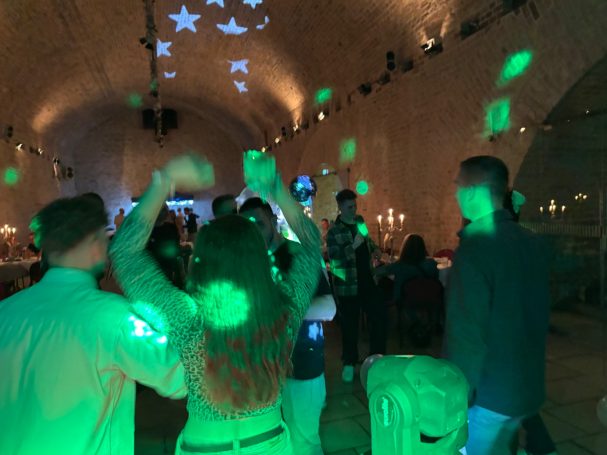 Tanzende Menschen in einem beleuchteten Raum mit grünen Lichtern und Projektionen.