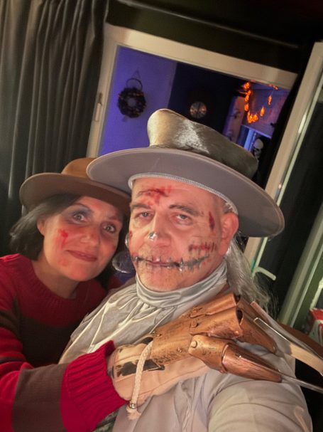 Zwei Personen in Kostümen mit Schminke, einem als Monster und einer mit Hut.