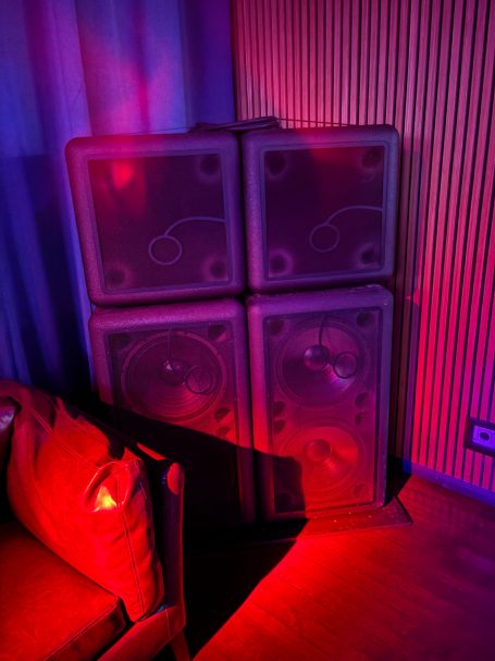 Vier Lautsprecherboxen in einer dunklen Umgebung mit rotem und blauen Licht.