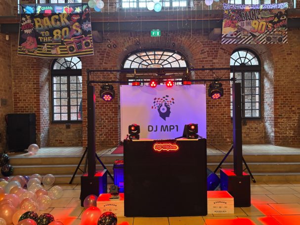 DJ-Pult mit bunten Lichtern und Dekoration in einer festlichen Veranstaltungsstätte.