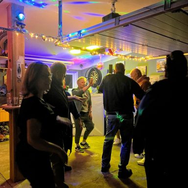Menschen tanzen und feiern in einer beleuchteten Garage mit Musik.