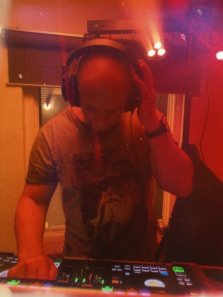 DJ spielt Musik mit Kopfhörern in einem beleuchteten Raum.