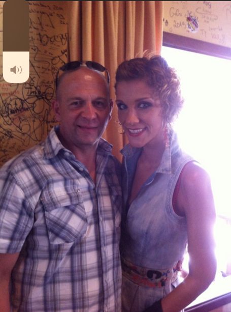 Mann und Frau stehen eng beieinander und lächeln vor einem Fensteraussicht.