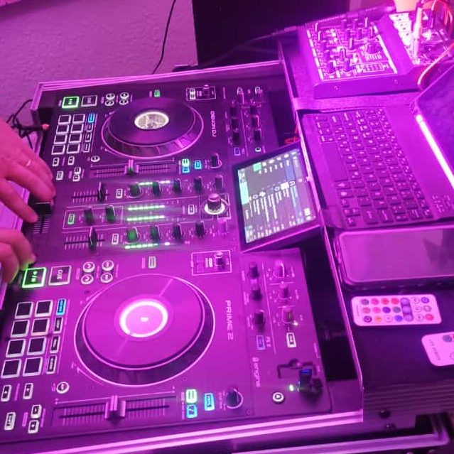 DJ-Pult mit Plattenspielern, Laptop und bunten Lichtern.